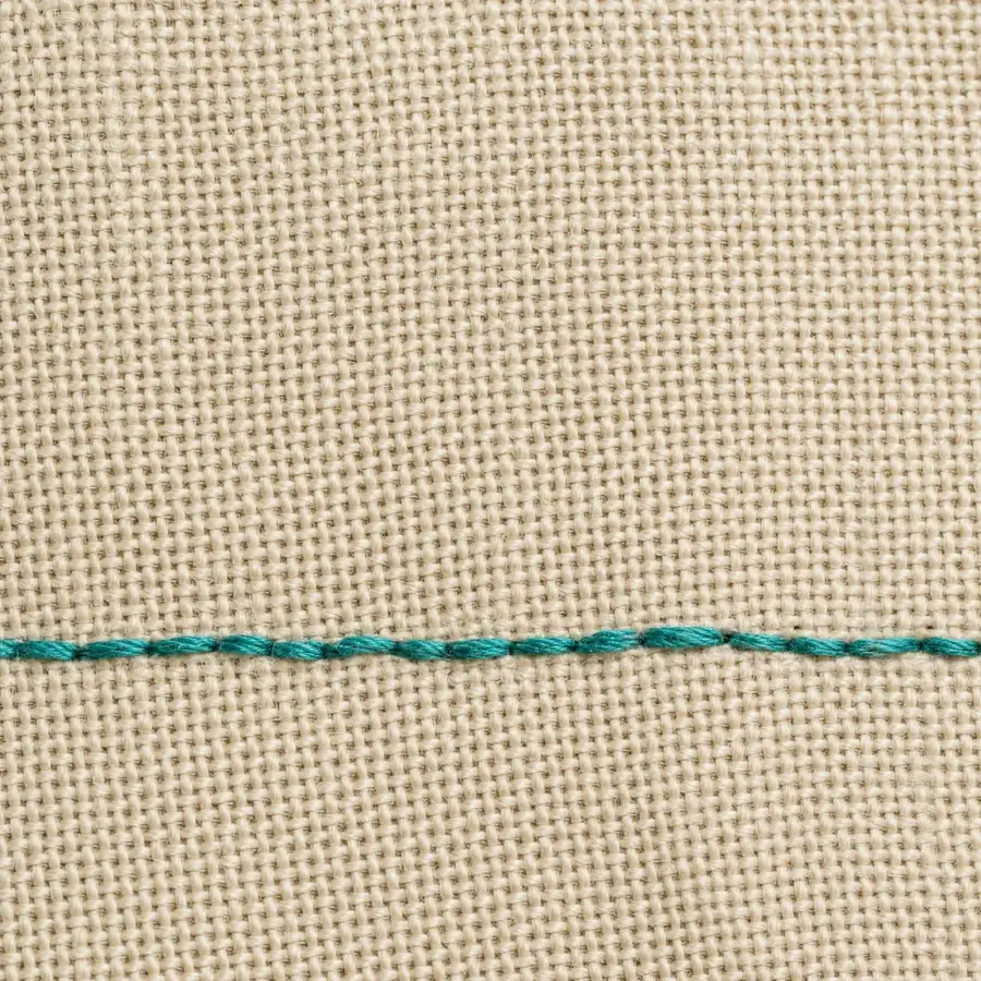 Macro of ecru fabric weave with a single teal stitch
