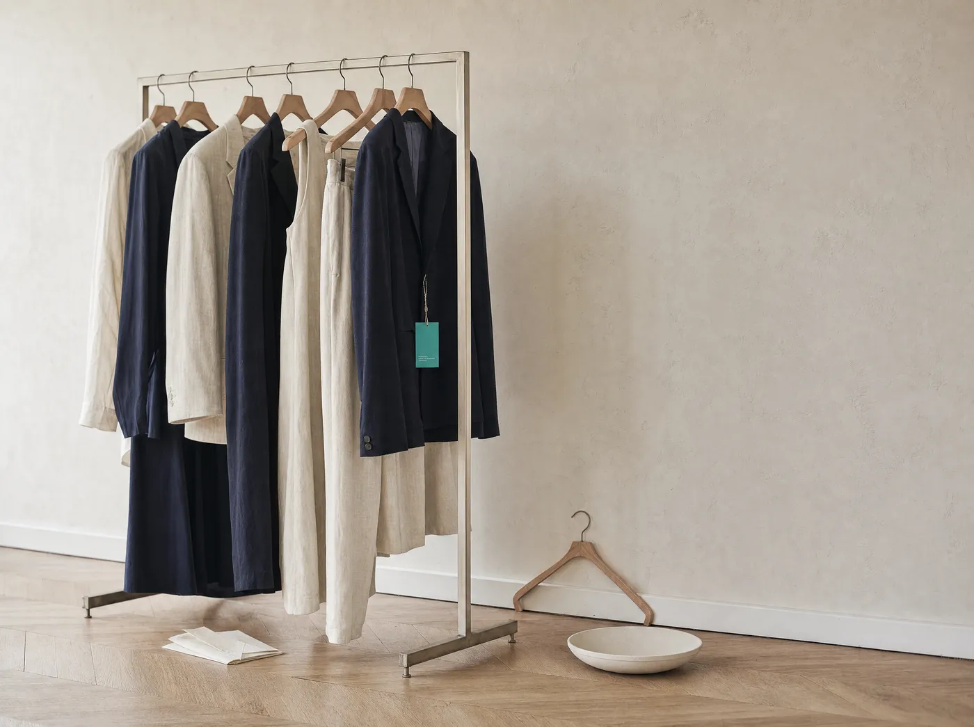 Garment rack with neutral fashion pieces, one carrying a teal DPP hangtag